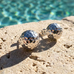 Two silver metallic balls on a textured stone surface with a pool in the background.