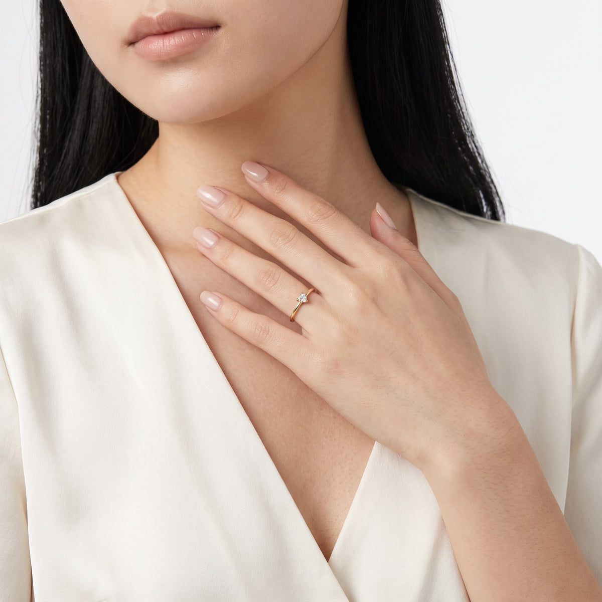 Hand resting at the collarbone wearing Aimée gold heart ring