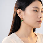 Model wearing the Lelice Alice Clover Earrings in gold, turned toward the light