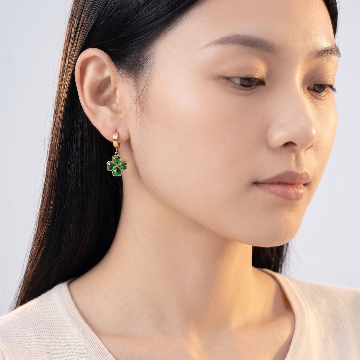 Model wearing the Lelice Alice Clover Earrings in gold, downcast beauty portrait