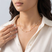 Hand at the collar of a woman wearing the Amalfi Pearl Necklace