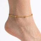 Close-up of the Lelice Amara Beaded Glow Anklet in gold on a woman's ankle