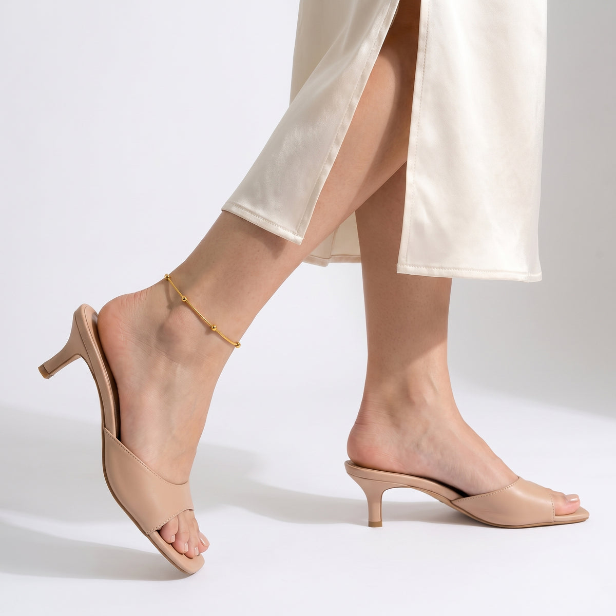 Woman mid-step through a skirt slit wearing the Amara Beaded Glow Anklet
