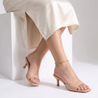Seated woman with ankles crossed wearing the Amara Beaded Glow Anklet