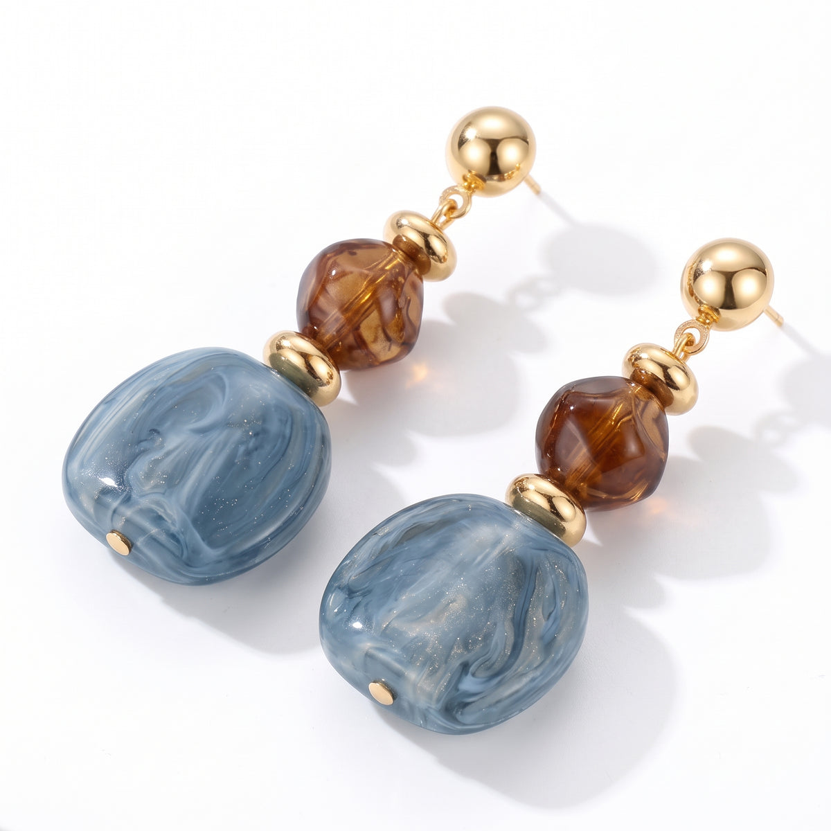 Lelice Amara Blue Marbled Acrylic Statement Drop Earrings in gold on a white background