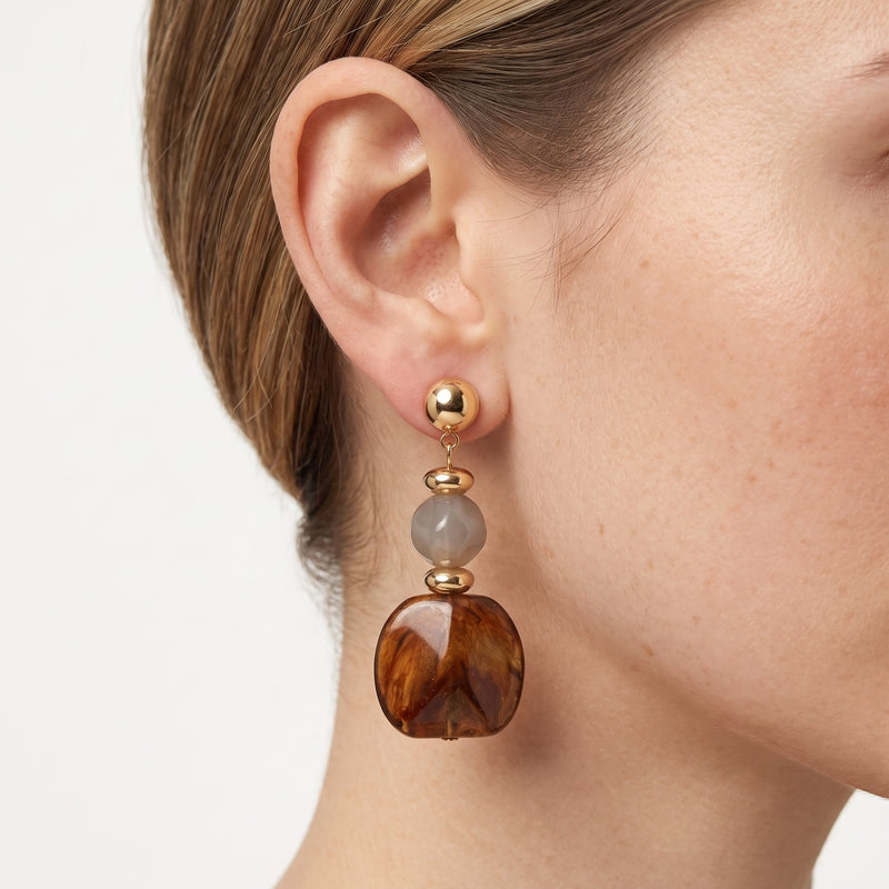 Close-up of the Lelice Amara Brown Marbled Acrylic Statement Drop Earrings in gold on the ear