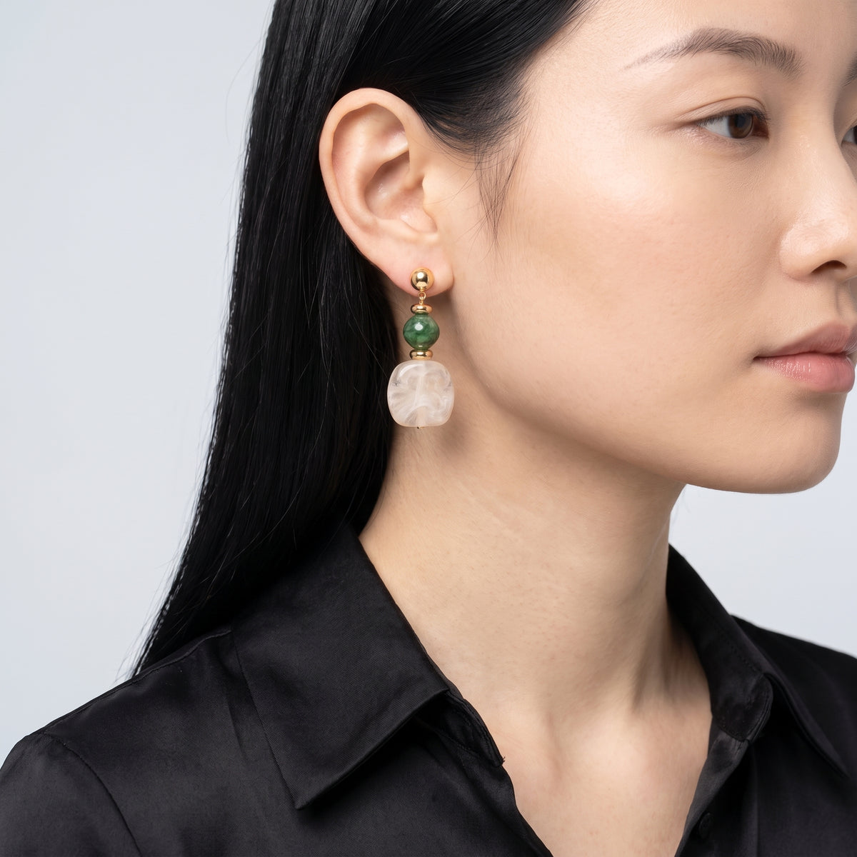 Model wearing the Lelice Amara White Marbled Acrylic Statement Drop Earrings in gold, turned toward the light