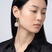 Model wearing the Lelice Amara White Marbled Acrylic Statement Drop Earrings in gold, downcast beauty portrait