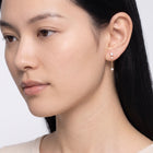 Model wearing the Lelice Andromeda Drop Earrings in gold, downcast beauty portrait