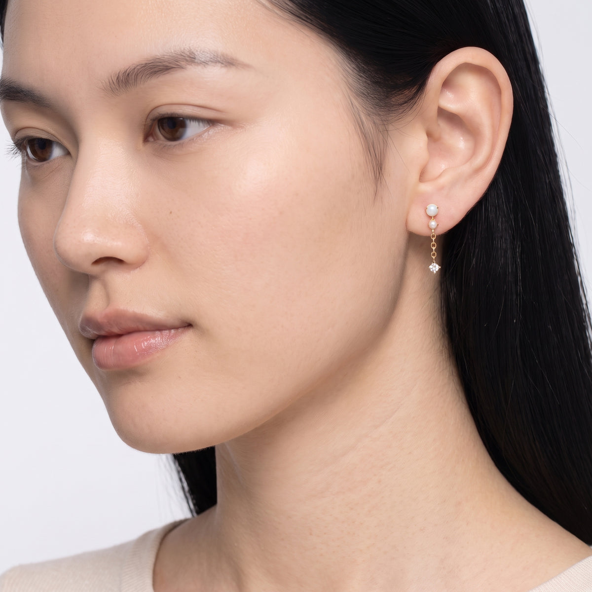 Model wearing the Lelice Andromeda Drop Earrings in gold, downcast beauty portrait