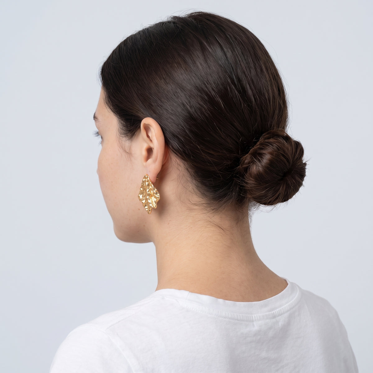 Model wearing the Lelice Artisan Ripple Studs in gold, low bun, ear and neck