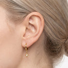 Close-up of the Lelice Astra Sunburst Huggies in gold on the ear