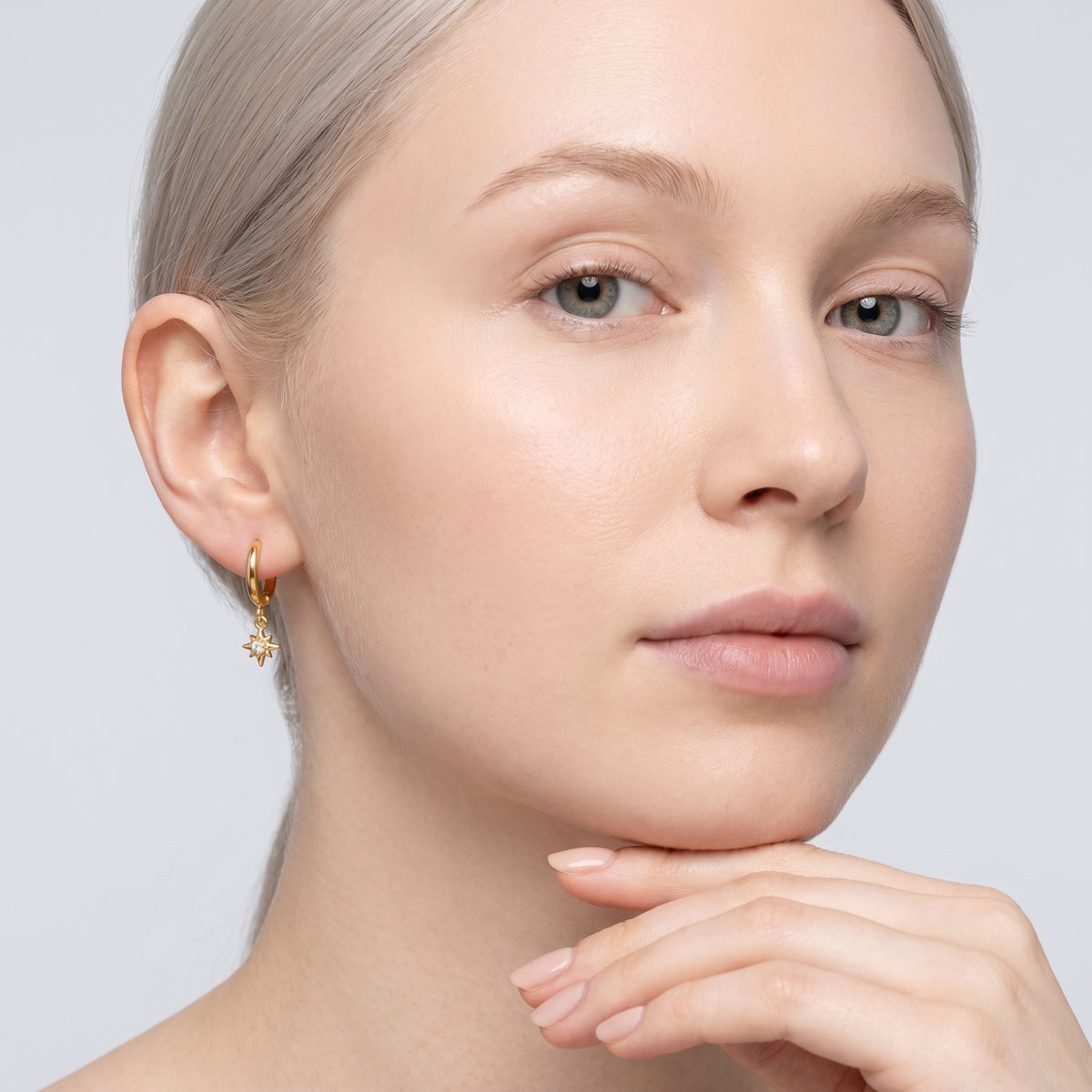 Model wearing the Lelice Astra Sunburst Huggies in gold, hand at the chin