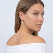 Model wearing the Lelice Astra Sunburst Silver Huggies, over-the-shoulder glance