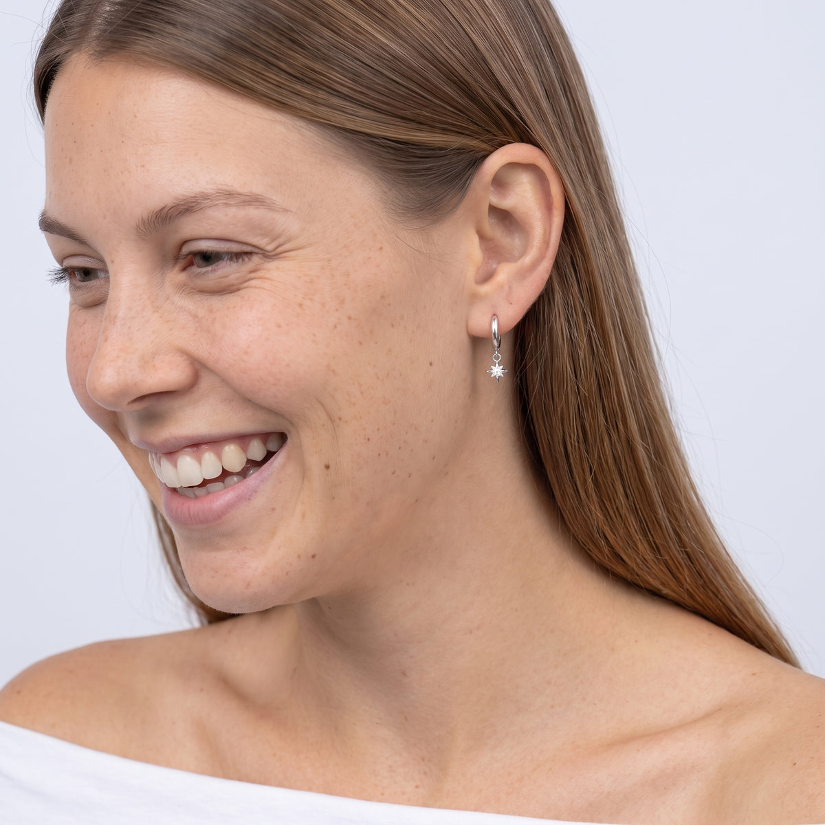 Model wearing the Lelice Astra Sunburst Silver Huggies, candid laugh