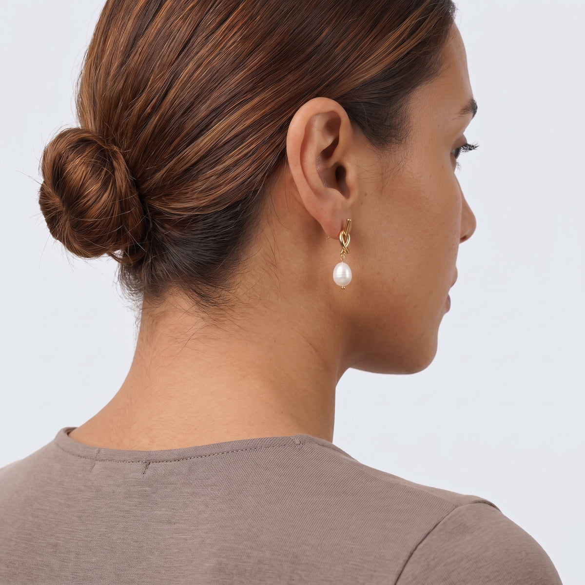 Model wearing the Lelice Brigitte Pearl Earrings in gold, low bun, ear and neck