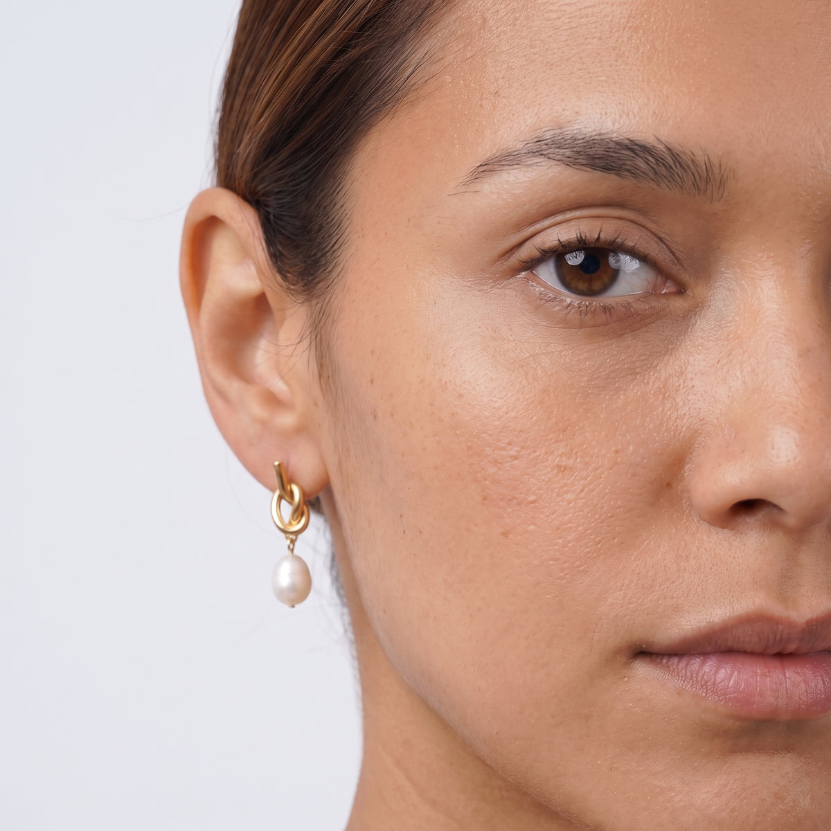 Model wearing the Lelice Brigitte Pearl Earrings in gold, one-eye face close-up