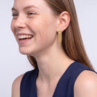Model wearing the Lelice Cascade Earrings in gold, candid laugh