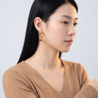 Model wearing the Lelice Claire Polished Hoops in gold, turned toward the light