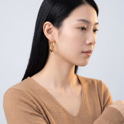 Model wearing the Lelice Claire Polished Hoops in gold, turned toward the light