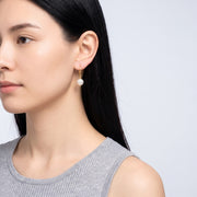 Model wearing the Lelice Clémence Pearl Earrings in gold, turned toward the light
