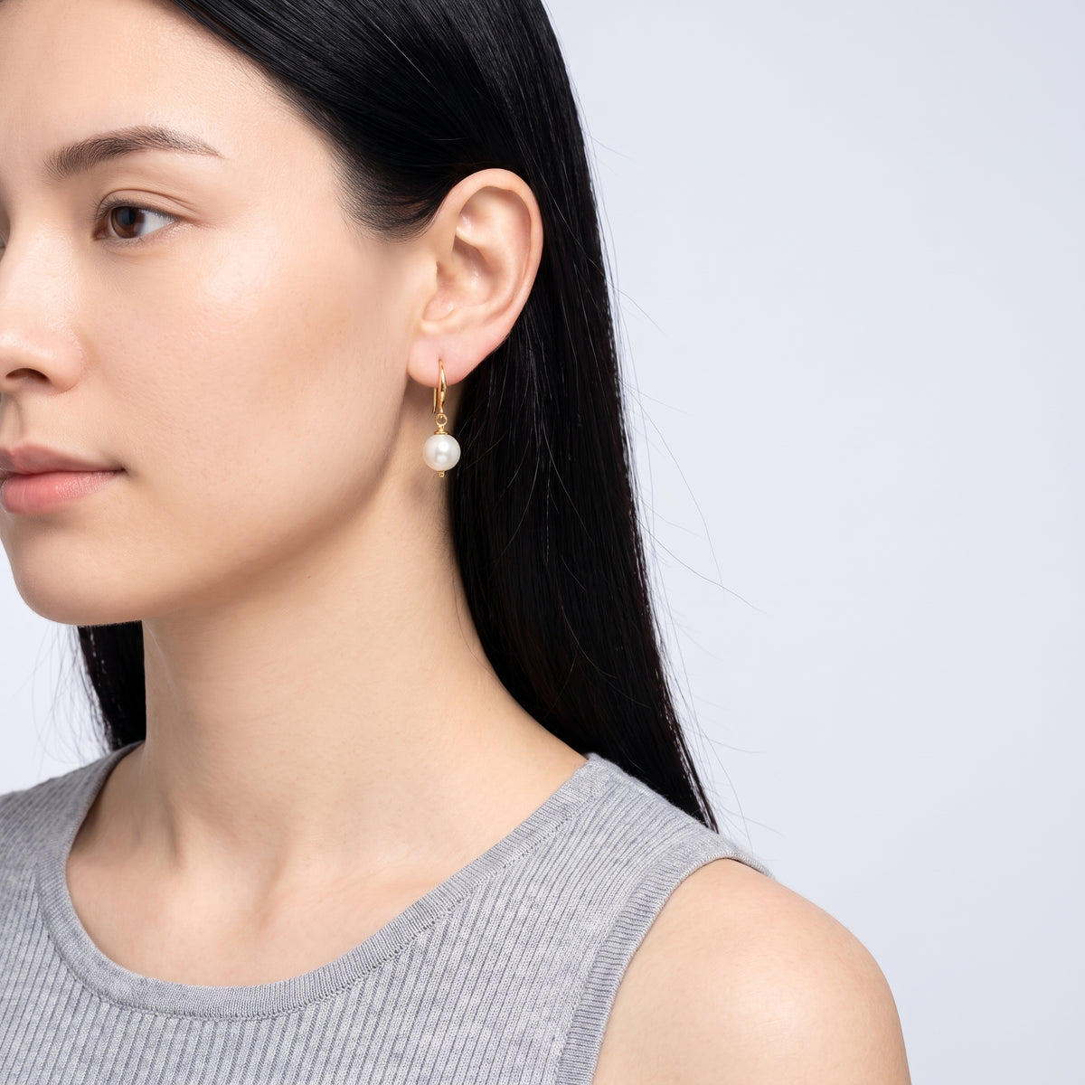 Model wearing the Lelice Clémence Pearl Earrings in gold, turned toward the light