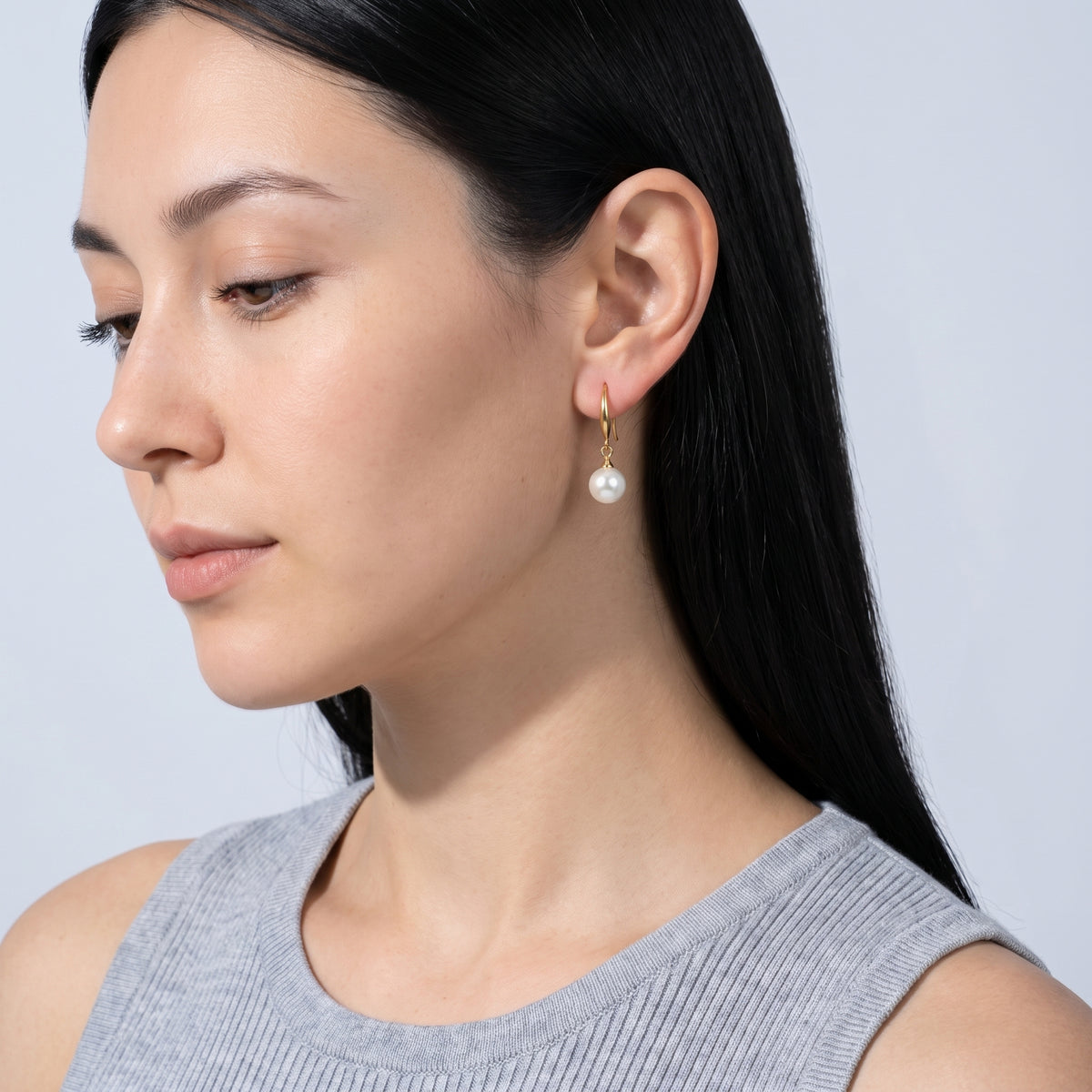 Model wearing the Lelice Clémence Pearl Earrings in gold, downcast beauty portrait
