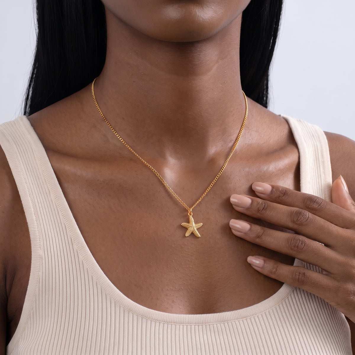 Hand at the collar of a woman wearing the Coastal Tide Necklace