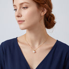 Neckline profile with hair up, wearing the Cora Pearl Drop Necklace