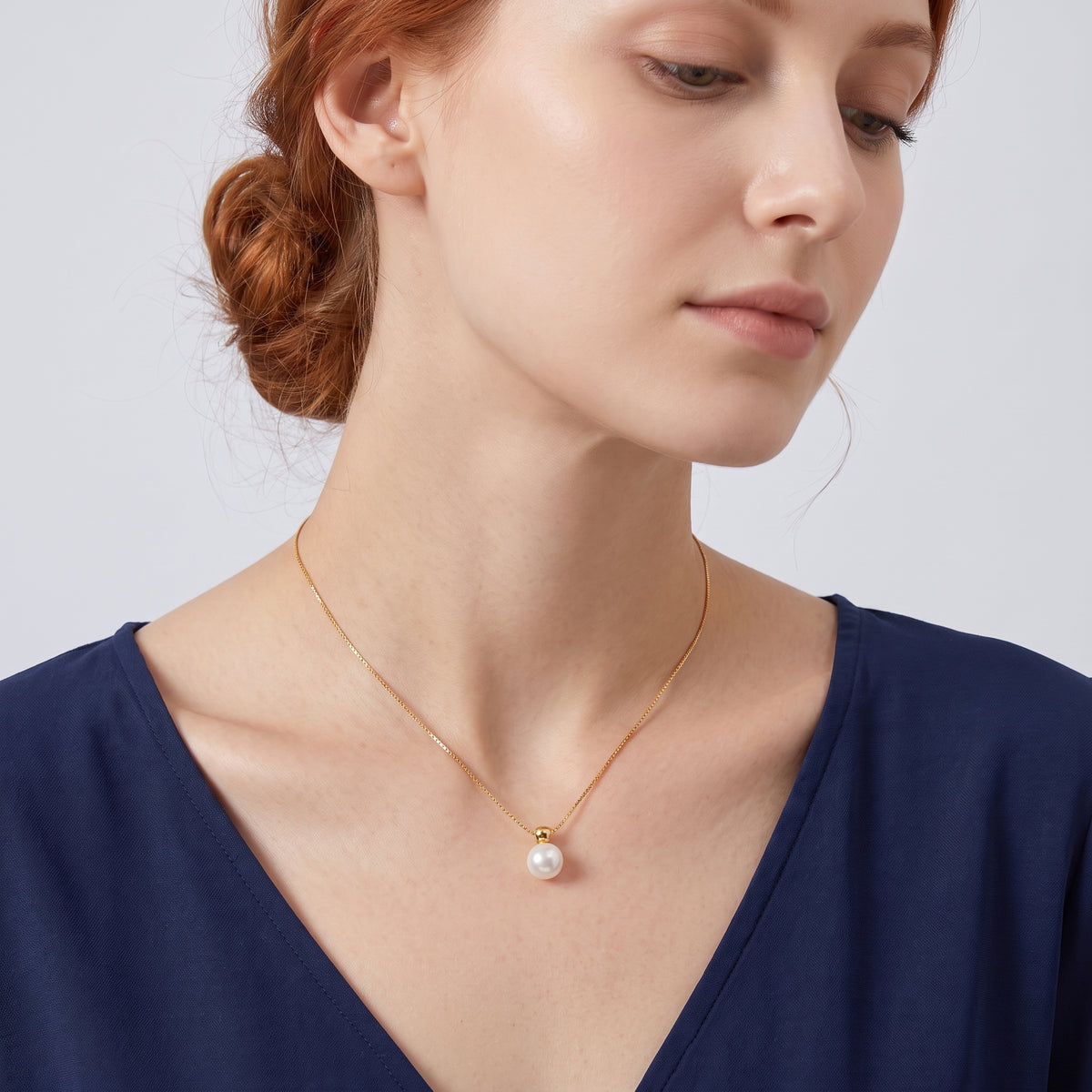 Low-angle portrait of a woman wearing the Cora Pearl Drop Necklace