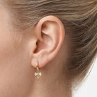 Close-up of the Lelice Dainty Bow Gold Hoops on the ear
