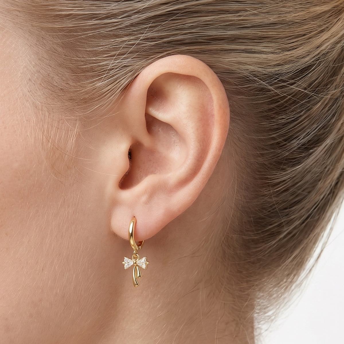Close-up of the Lelice Dainty Bow Gold Hoops on the ear