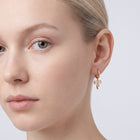 Model wearing the Lelice Dainty Bow Gold Hoops, one-eye face close-up