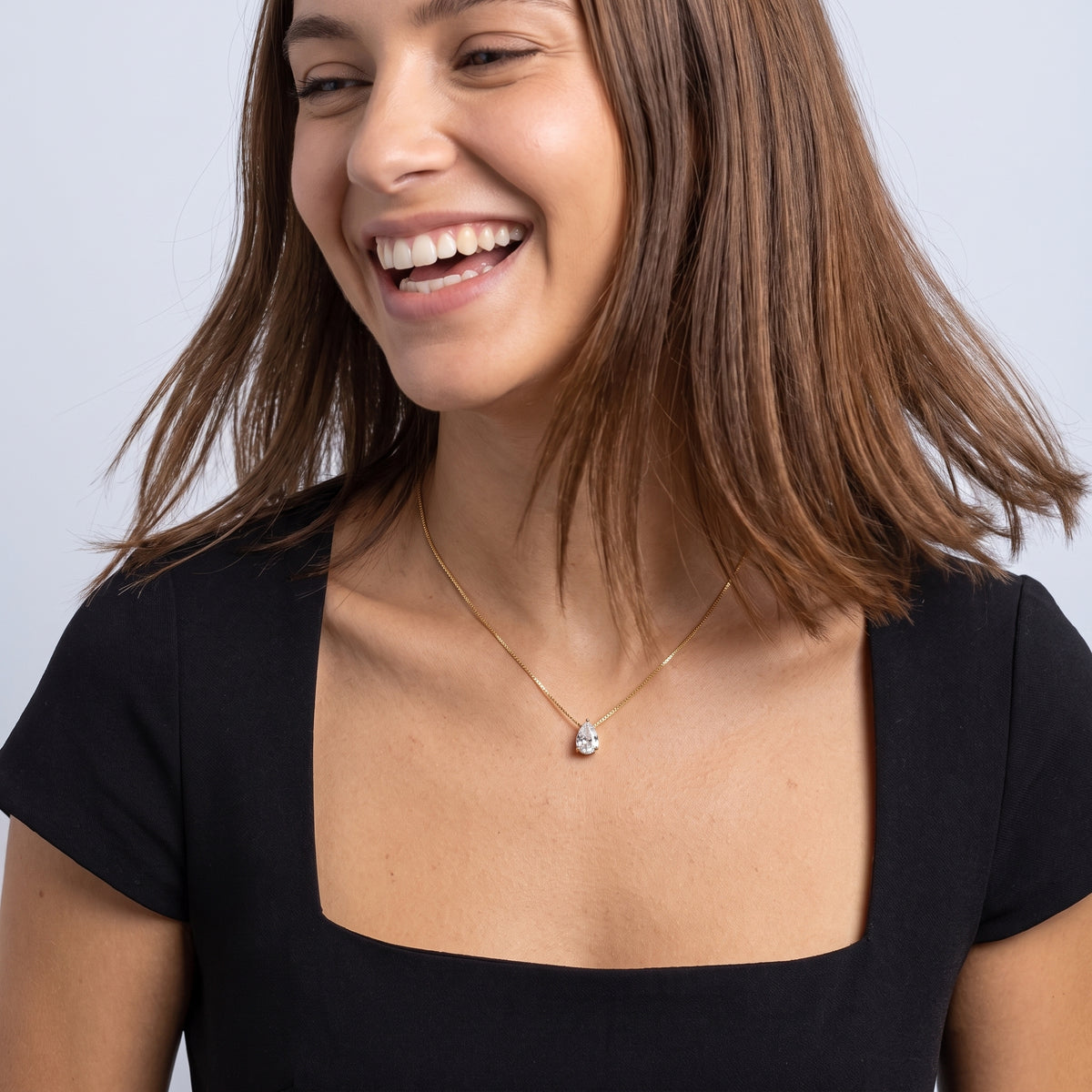 Laughing woman wearing the Dainty Pear Drop Gold Necklace