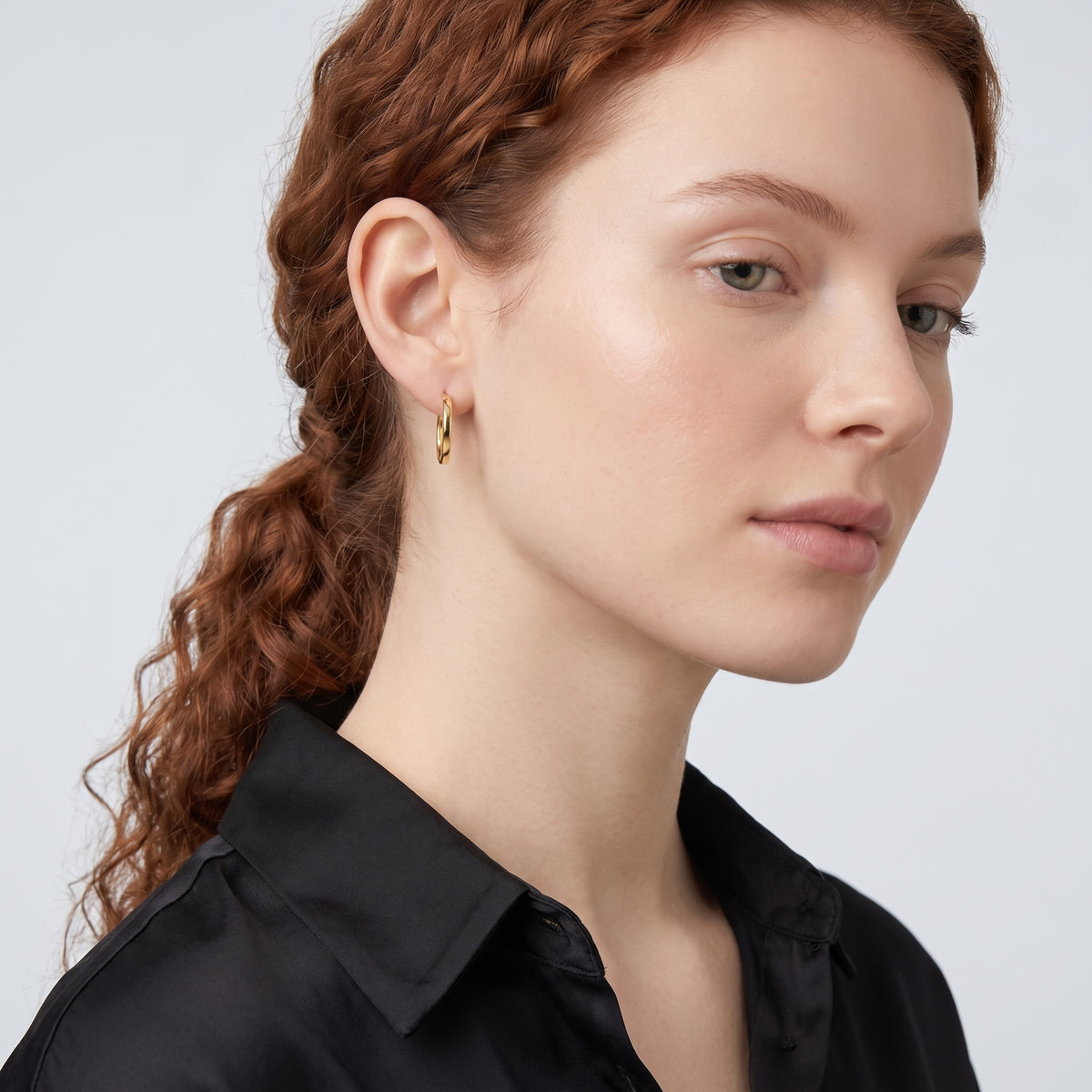 Model wearing the Lelice Diane Hoop Earrings in gold, serene chin lift