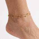 Close-up of the Lelice Elara Double Strand Anklet in gold on a woman's ankle