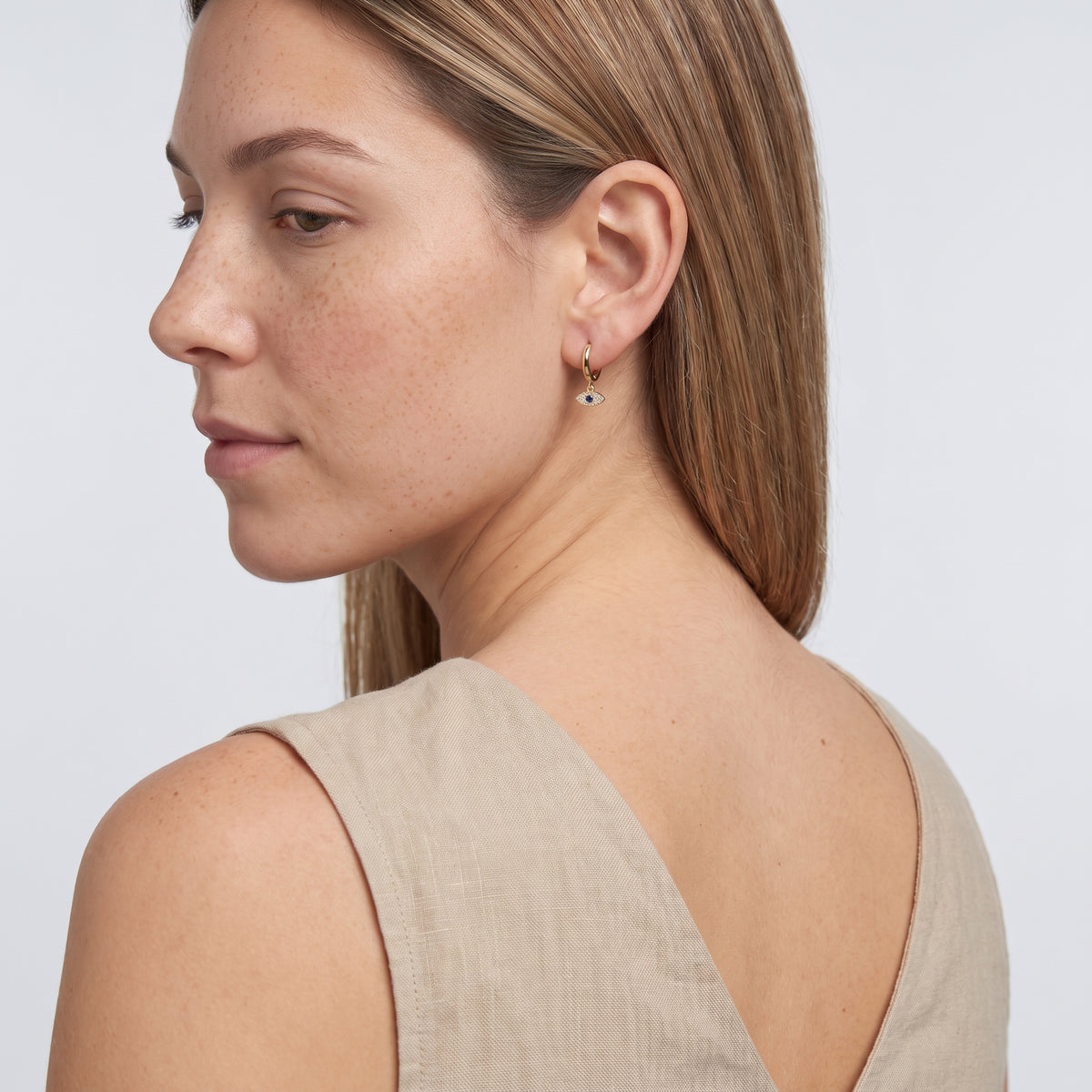 Model wearing the Lelice Elena Protection Earrings in gold, over-the-shoulder glance
