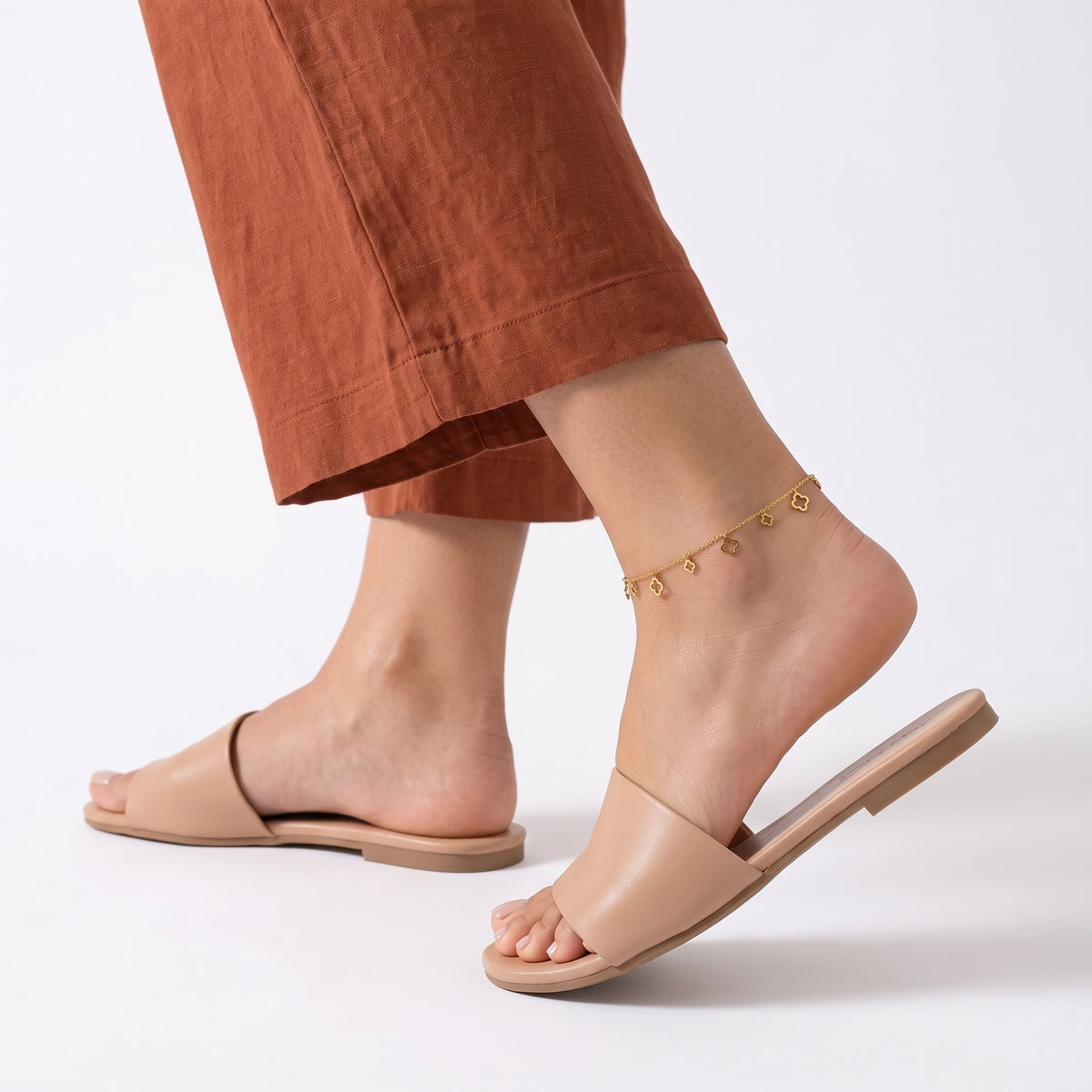 Woman walking away in the Elina Clover Frame Anklet, heel lifted