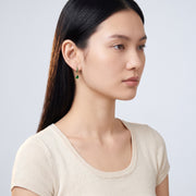 Model wearing the Lelice Esme Emerald Hoops in gold, turned toward the light