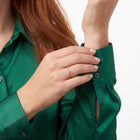 Hand holding a sleeve cuff wearing Estelle gold wave ring