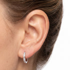 Close-up of the Lelice Evelyn Infinity Hoops in silver on the ear