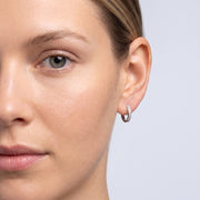 Model wearing the Lelice Evelyn Infinity Hoops in silver, one-eye face close-up