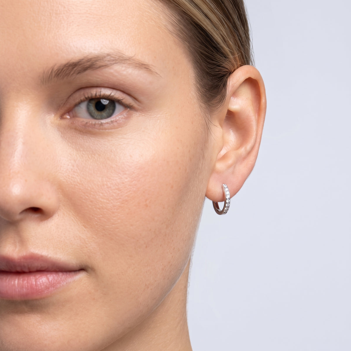 Model wearing the Lelice Evelyn Infinity Hoops in silver, one-eye face close-up