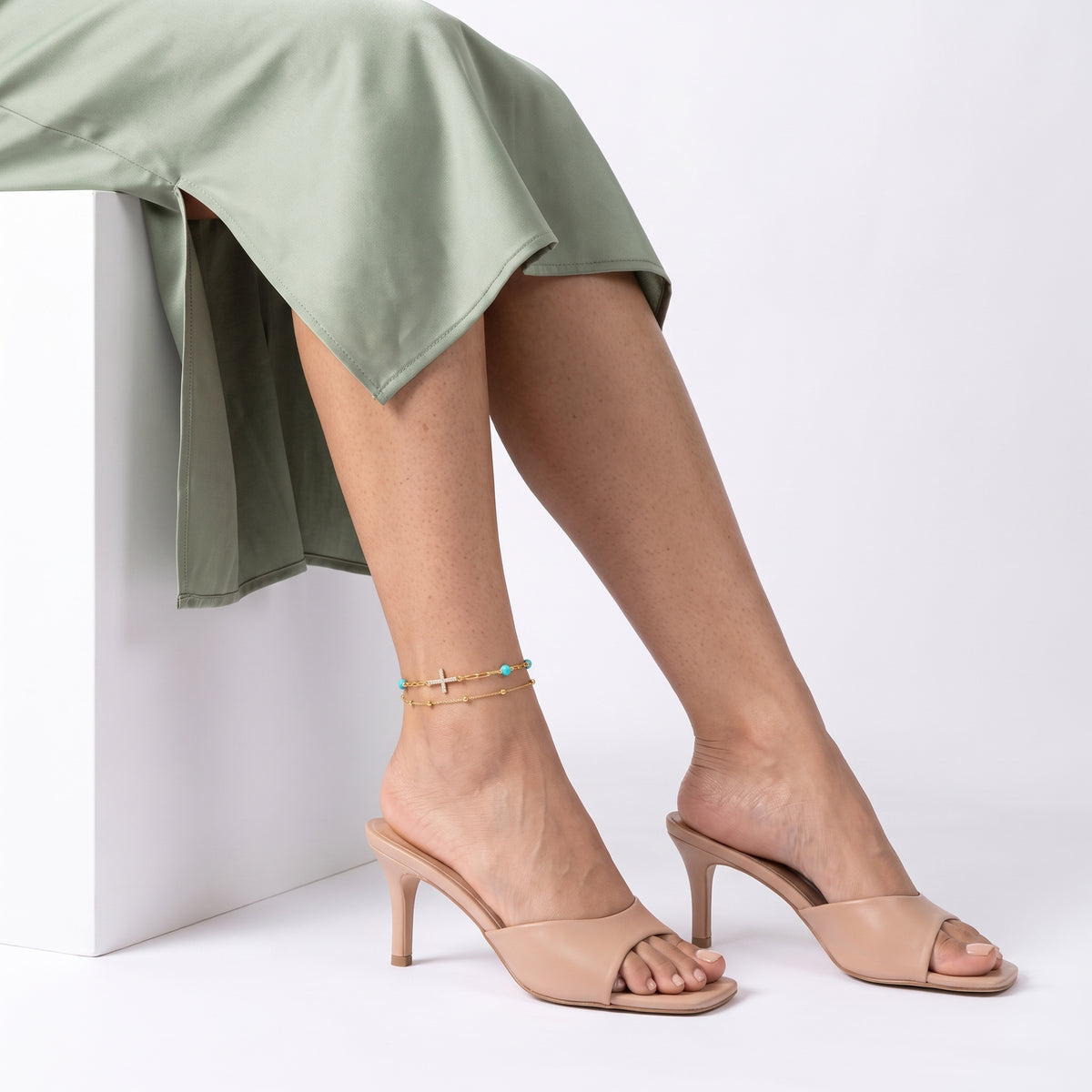 Seated woman with ankles crossed wearing the Faith Gold Anklet