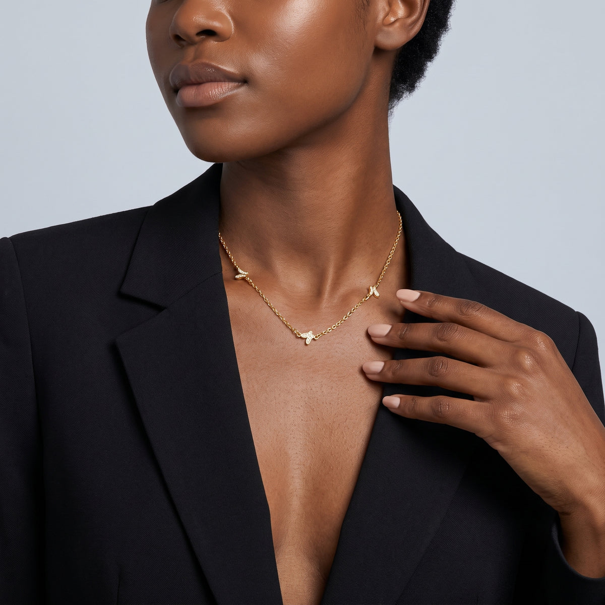 Hand at the collar of a woman wearing the Faye Butterfly Necklace