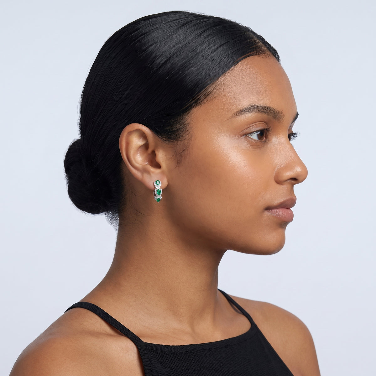 Model wearing the Lelice Forest Emerald Hoops in silver, slicked-back profile