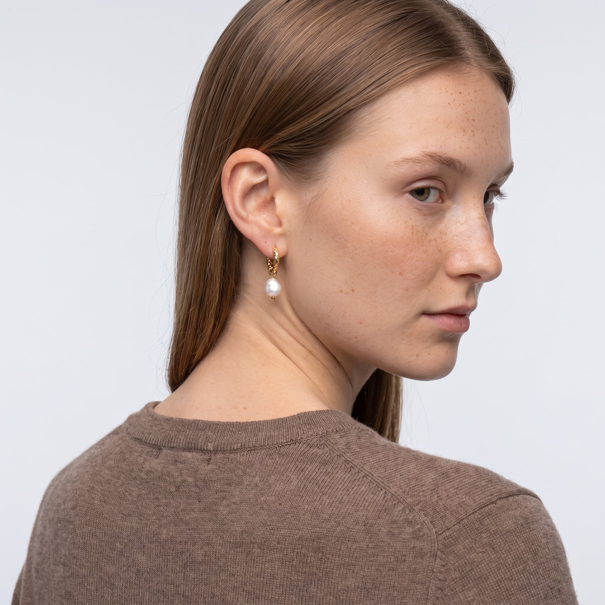 Model wearing the Lelice Gabrielle Pearl Hoops in gold, over-the-shoulder glance