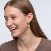 Model wearing the Lelice Gabrielle Pearl Hoops in gold, candid laugh