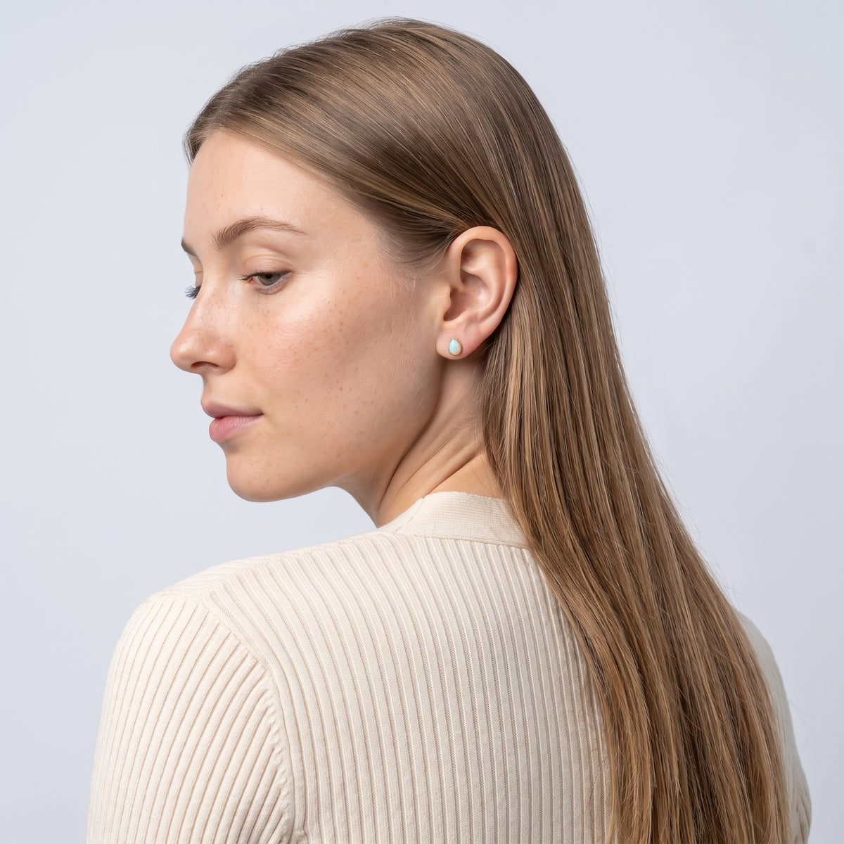 Model wearing the Lelice Giselle Opal Earrings in gold, over-the-shoulder glance