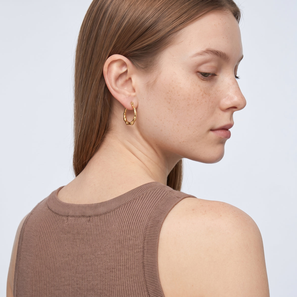 Model wearing the Lelice Golden Bamboo Hoops, over-the-shoulder glance